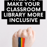 The hand of a white person is raised upward. On the back of the hand is a painting of the rainbow Pride flag. This appears under text that reads: Make Your Classroom Library More Inclusive with These 15 LGBTQ+ Titles